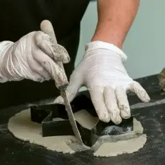 Rękawiczki i nóż pomagają w tworzeniu ozdób z betonu. Wycinanie kształtów z masy betonowej.