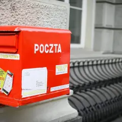 Czerwona skrzynka pocztowa z napisem "POCZTA" i naklejką o aplikacji Envelo. Jak wysłać list do Anglii? Wystarczy zaadresować kopertę i wrzucić do skrzynki.