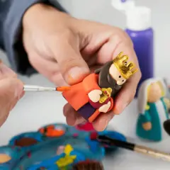 Tworzenie figurek do szopki z modeliny krok po kroku. Ręka maluje złotą koronę na głowie postaci.