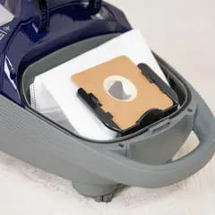 Worek do odkurzacza wewnątrz szarej obudowy. Na górze widoczny napis "Silent Suction System". Dowiedz się, ile decybeli ma odkurzacz.