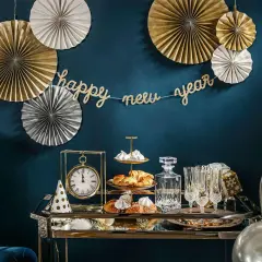 Złote i srebrne rozety, girlanda "happy new year" i eleganckie przekąski tworzą stylowe dekoracje sylwestrowe diy.