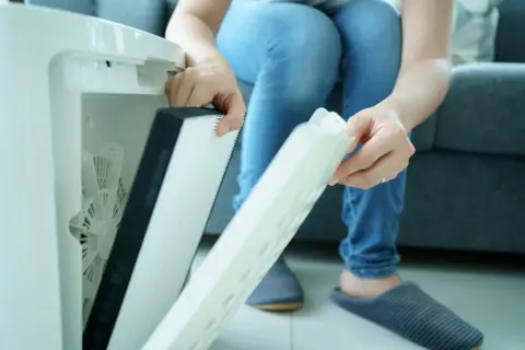 Osoba wymienia filtr w oczyszczaczu powietrza. Czy filtr HEPA można myć wodą? Nie, zazwyczaj nie.
