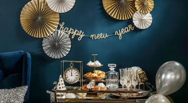 Złote i srebrne rozety, girlanda "happy new year" i eleganckie przekąski tworzą stylowe dekoracje sylwestrowe diy.