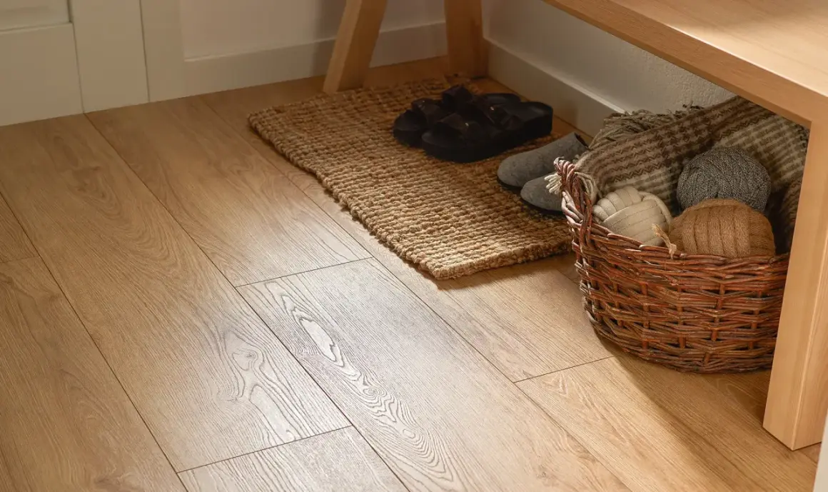 Jasna podłoga w przedpokoju w bloku, z dywanikiem, klapkami i koszem z włóczkami pod ławką.