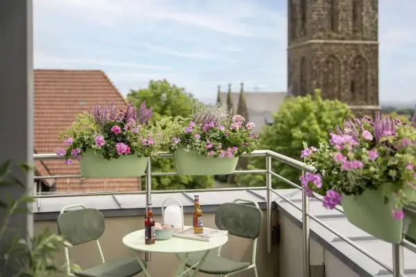 Kwiaty na balkon południowy: bujne, różowe i fioletowe kompozycje w zielonych skrzynkach, tworzące barwną oazę.