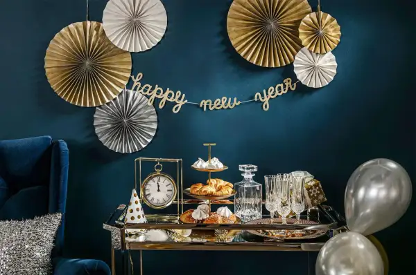 Złote i srebrne rozety, girlanda "happy new year" i eleganckie przekąski tworzą stylowe dekoracje sylwestrowe diy.